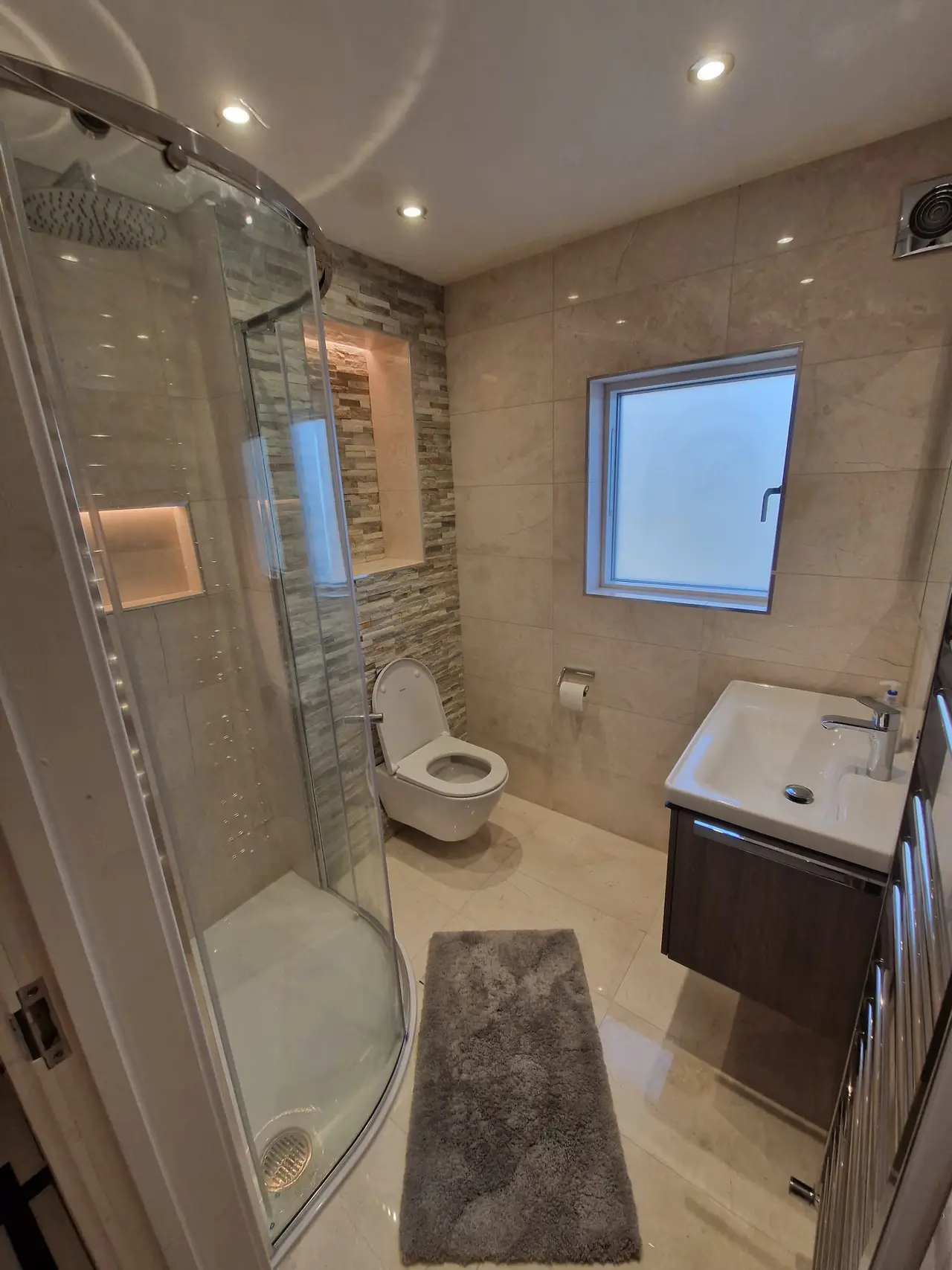 Finished beige shower room with a curved enclosure and dark wood vanity