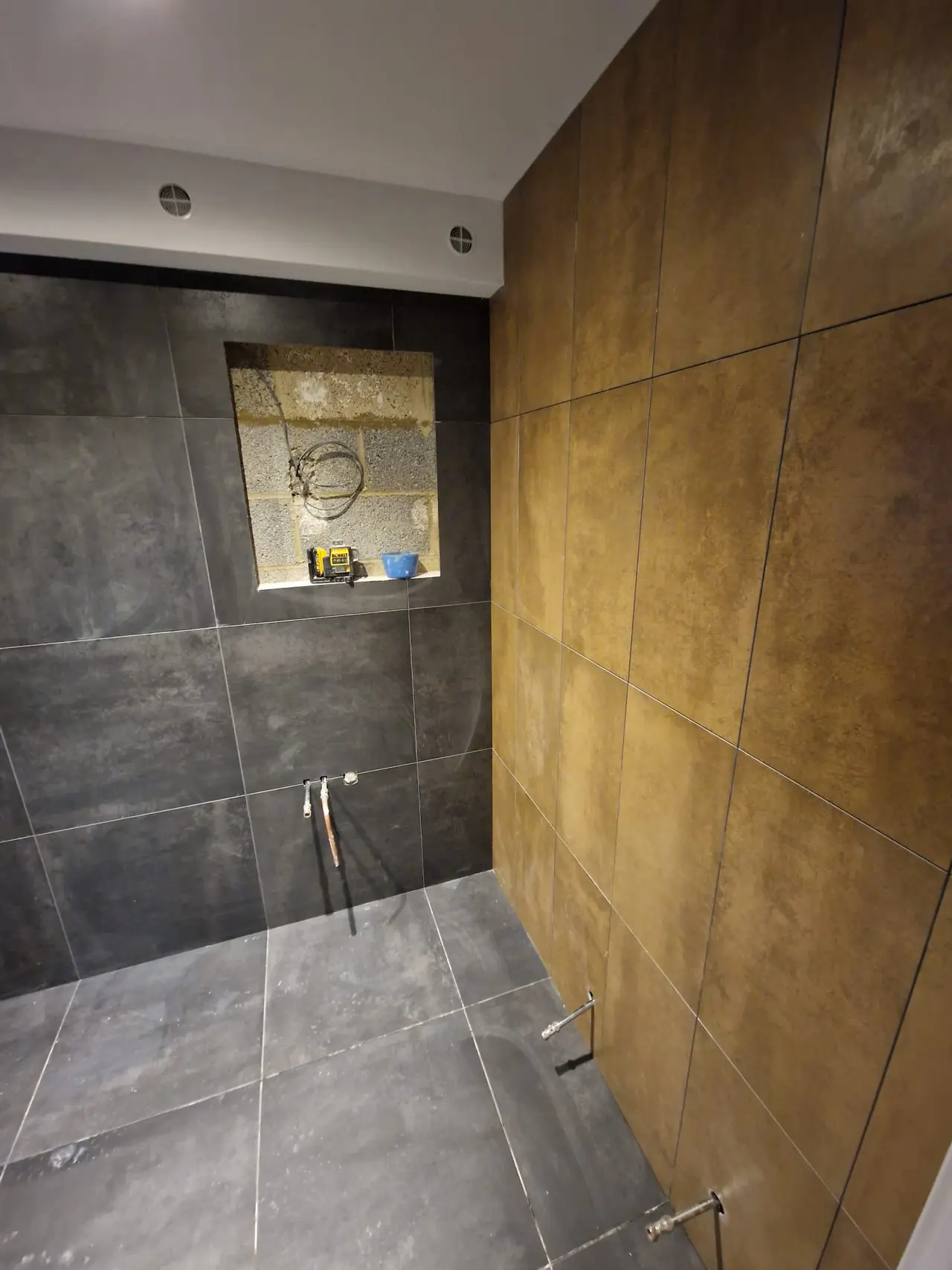 Black and bronze shower room with tiling complete and fittings still to install