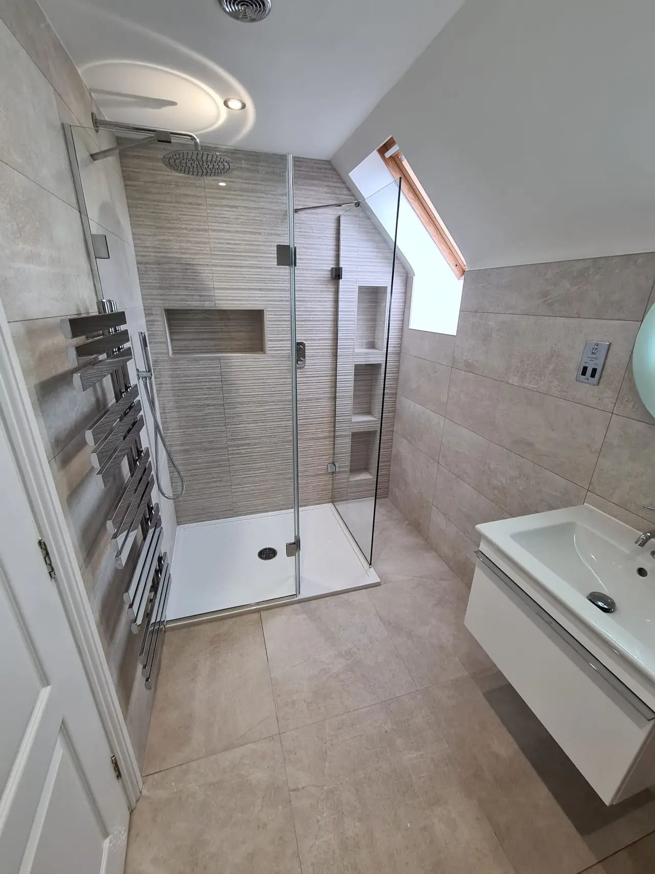 Finished loft shower room with a roof window and striped tiled feature wall