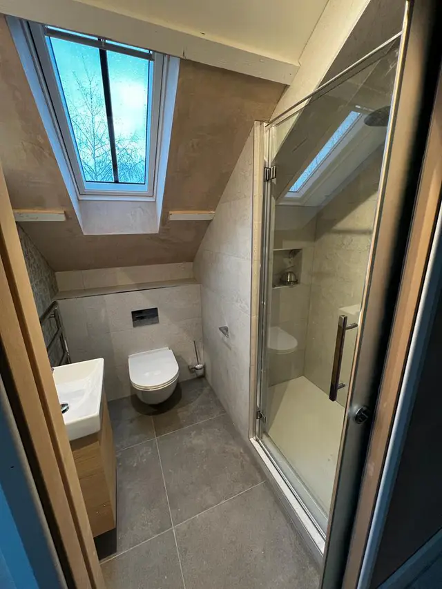 Compact loft bathroom with a roof window, shower and wall-hung toilet