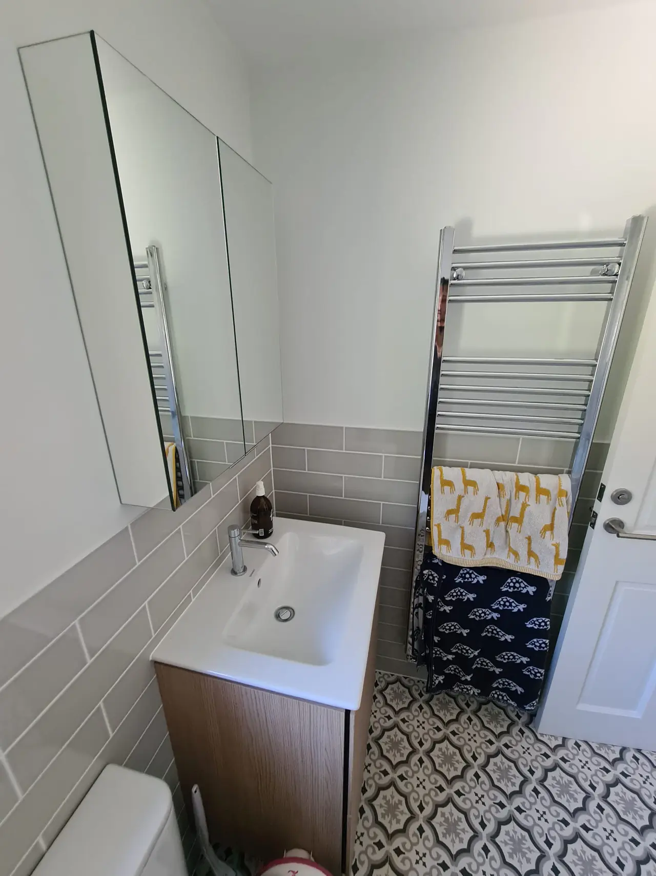 Small finished bathroom with grey metro tiles and a patterned floor