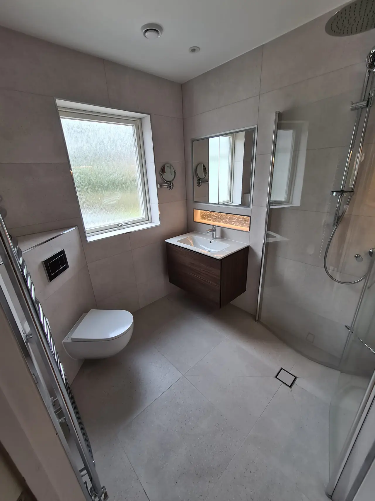 Finished pale wet room with wall-hung fittings and an open shower area