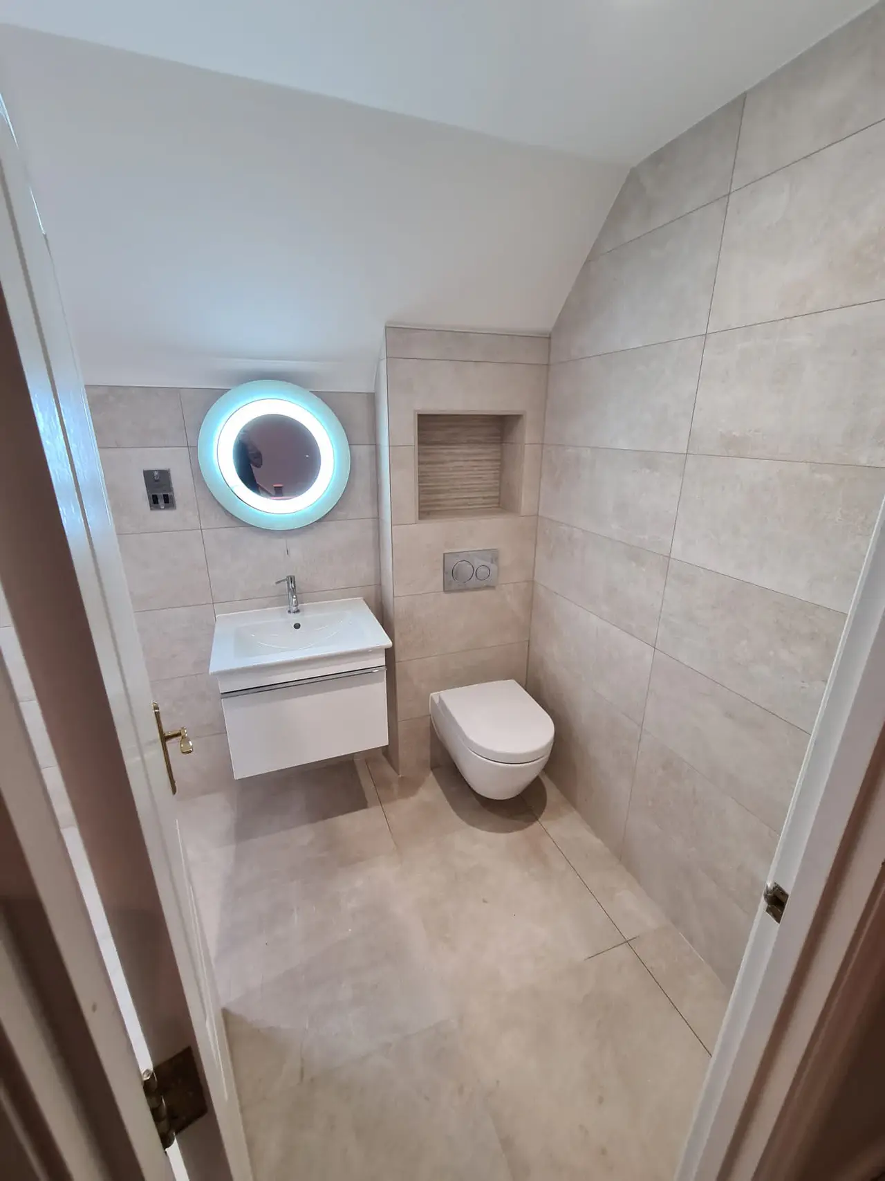 Finished pale stone cloakroom with wall-hung fittings and a floating vanity