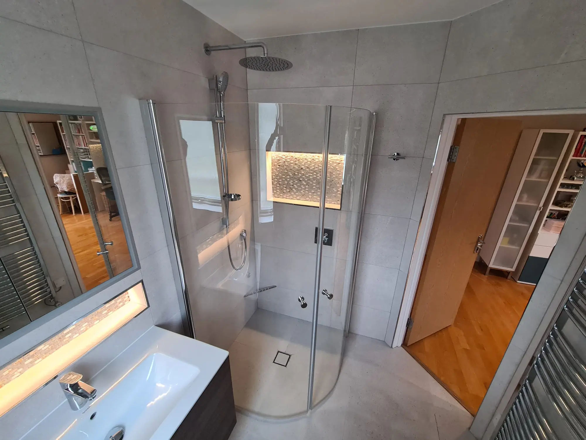 Grey wet room with a rainfall shower and illuminated mosaic niches