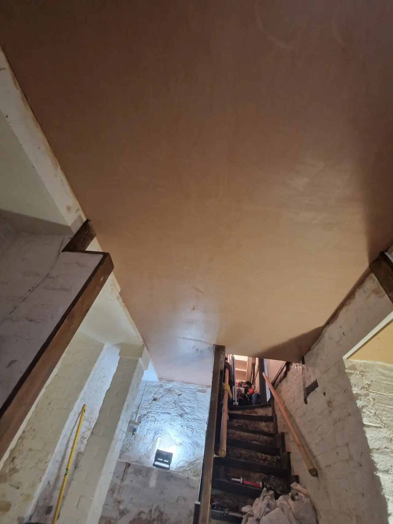 Newly plastered cellar ceiling above an existing staircase and masonry walls