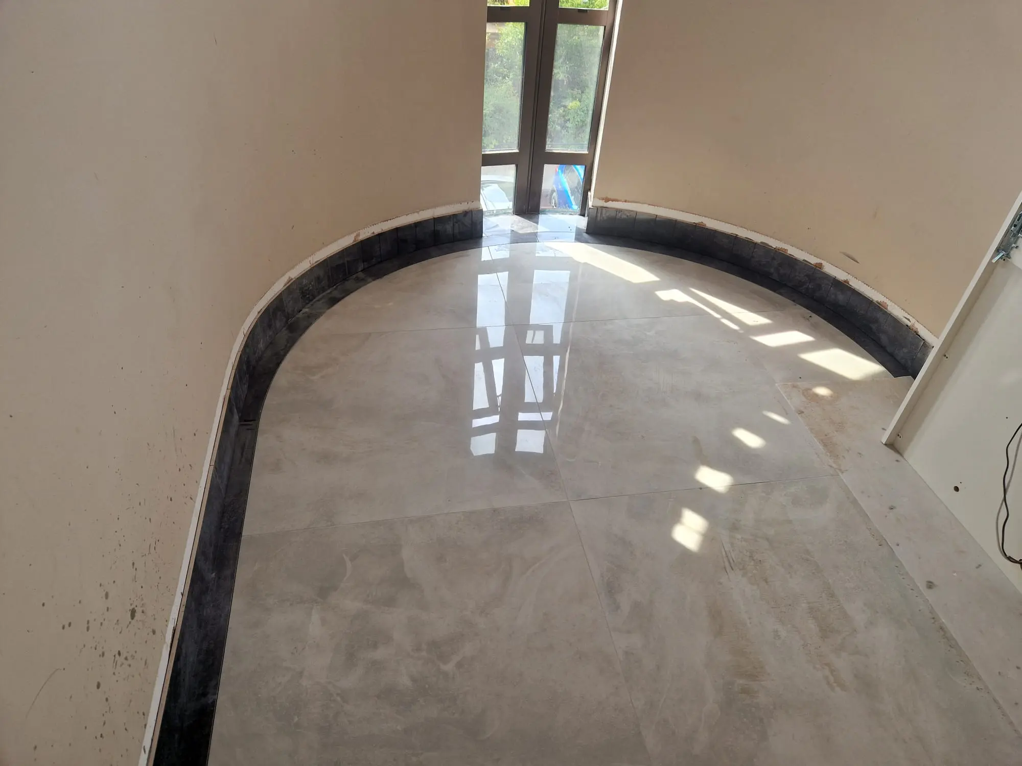 Polished tiled floor cut to follow a curved wall and dark border