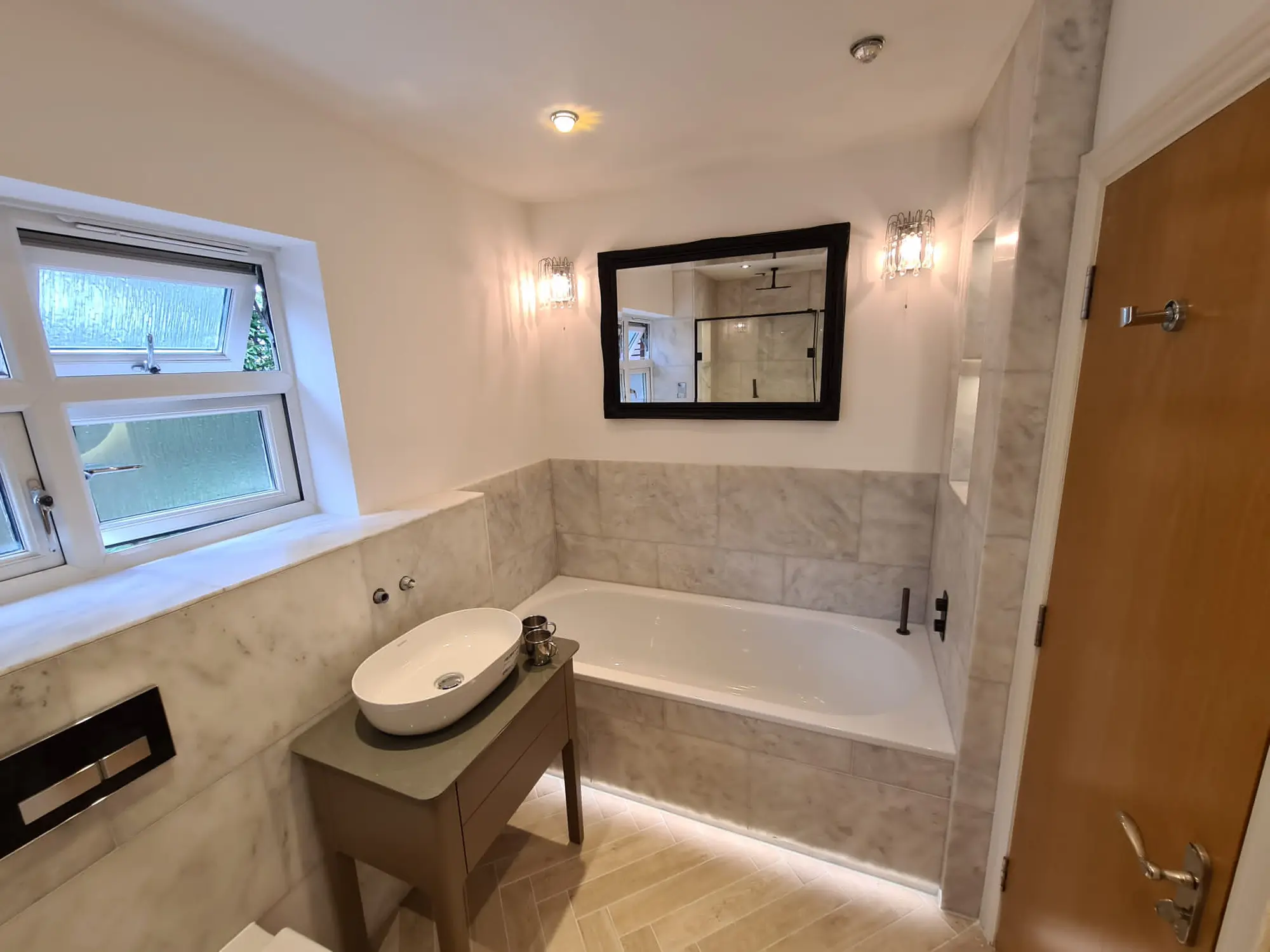 Marble-effect bathroom with a recessed bath and warm low-level lighting