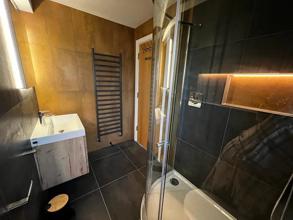 Bronze tiled wall and black shower enclosure in a finished shower room