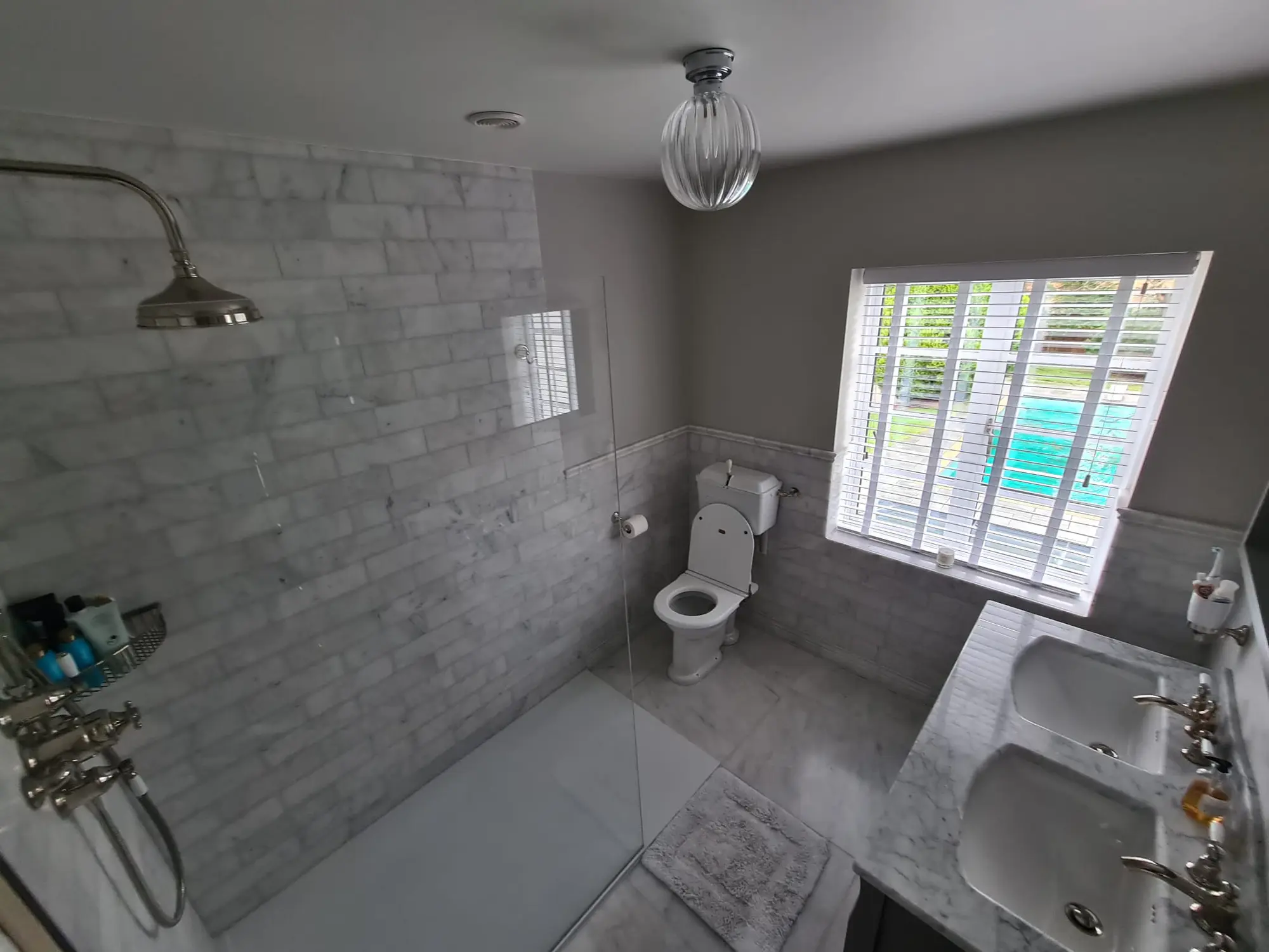 Traditional marble wet room with twin basins and exposed shower fittings