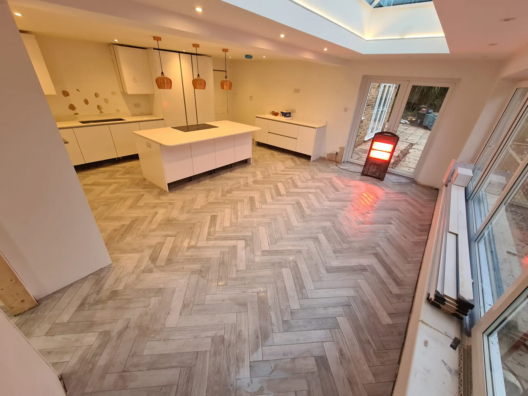 Bright white fitted kitchen with a central island and herringbone floor