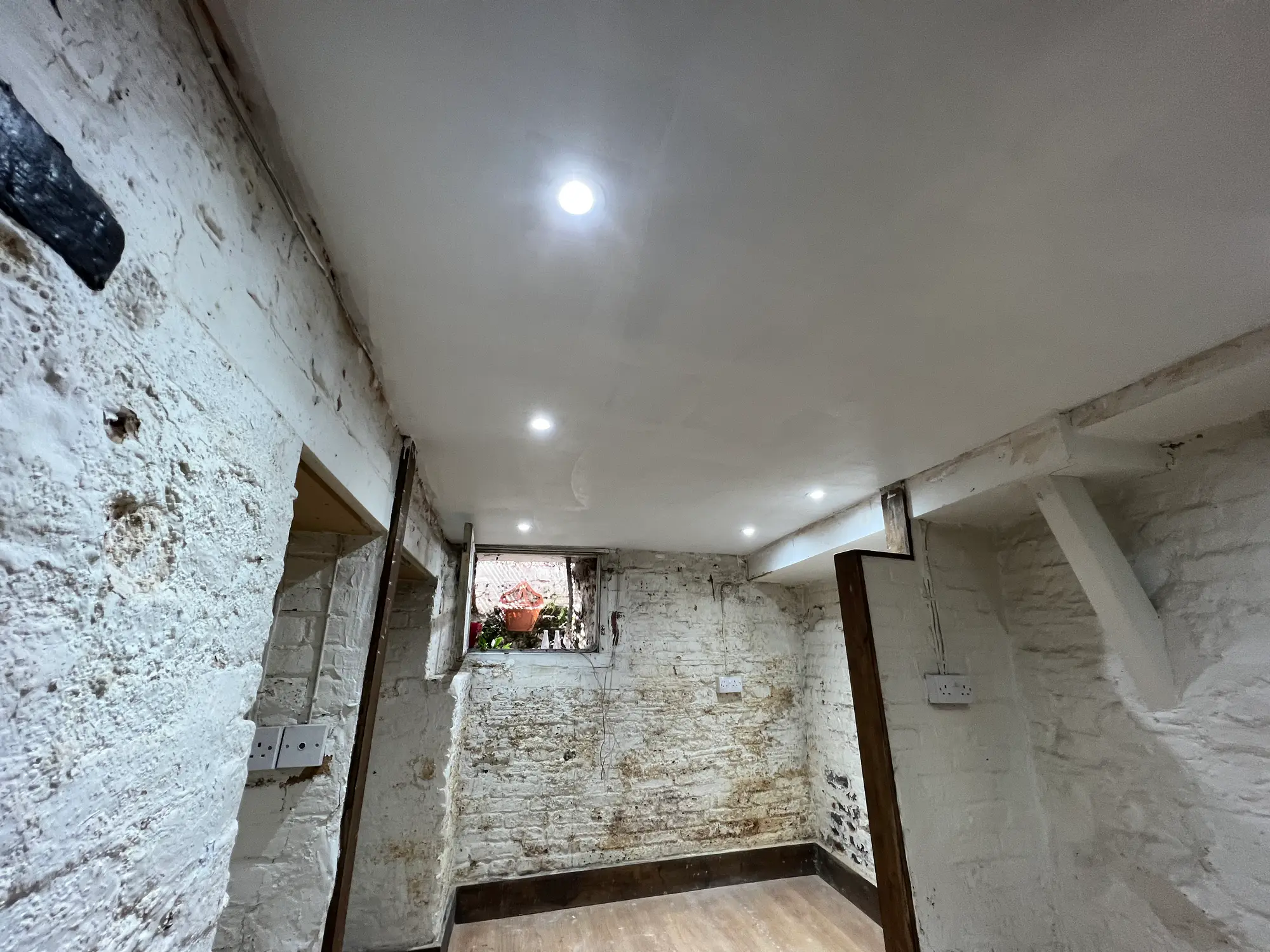 Stripped stone cellar with whitewashed walls and a newly finished ceiling