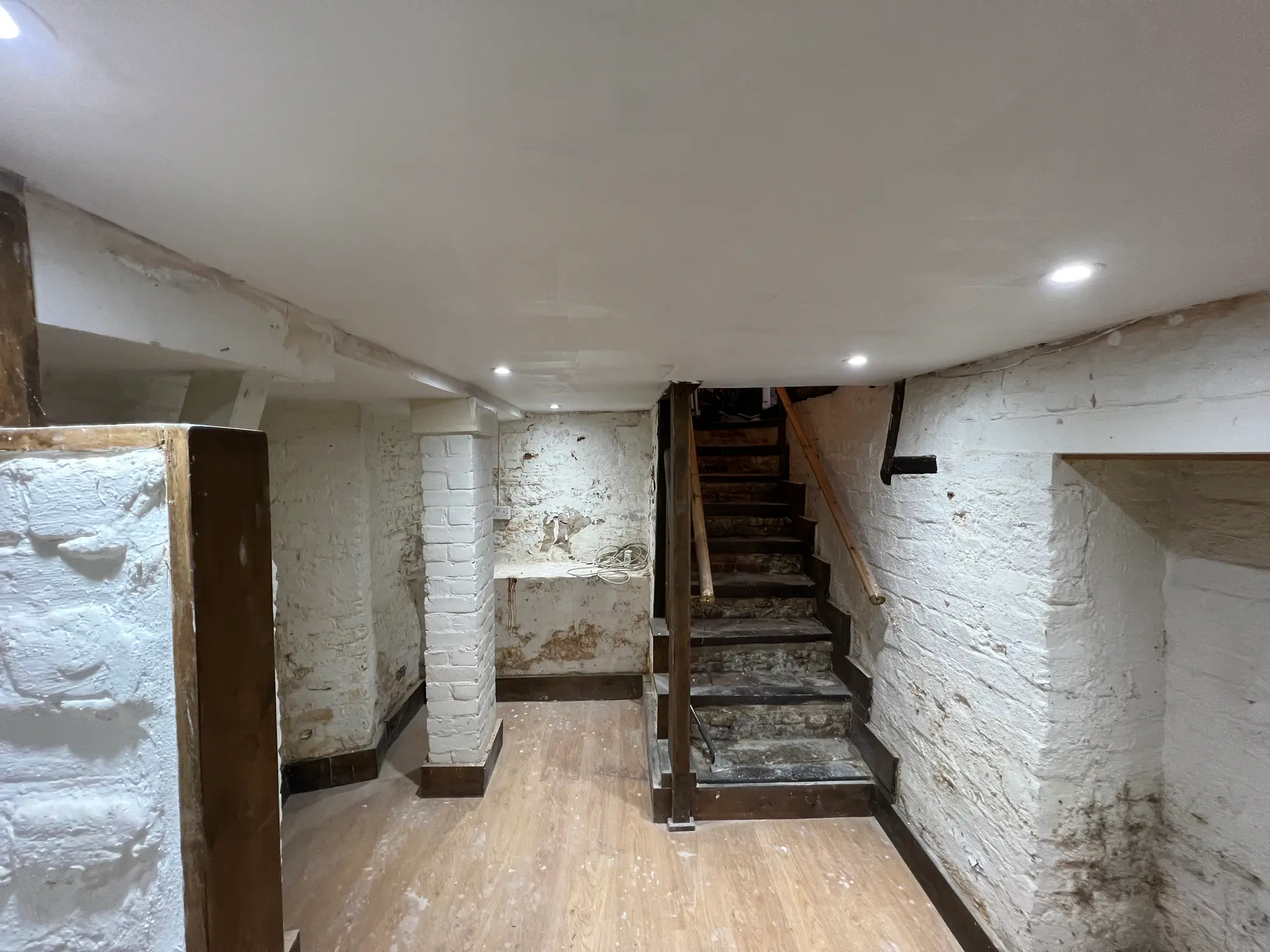 Renovated stone cellar with pale flooring and a central staircase