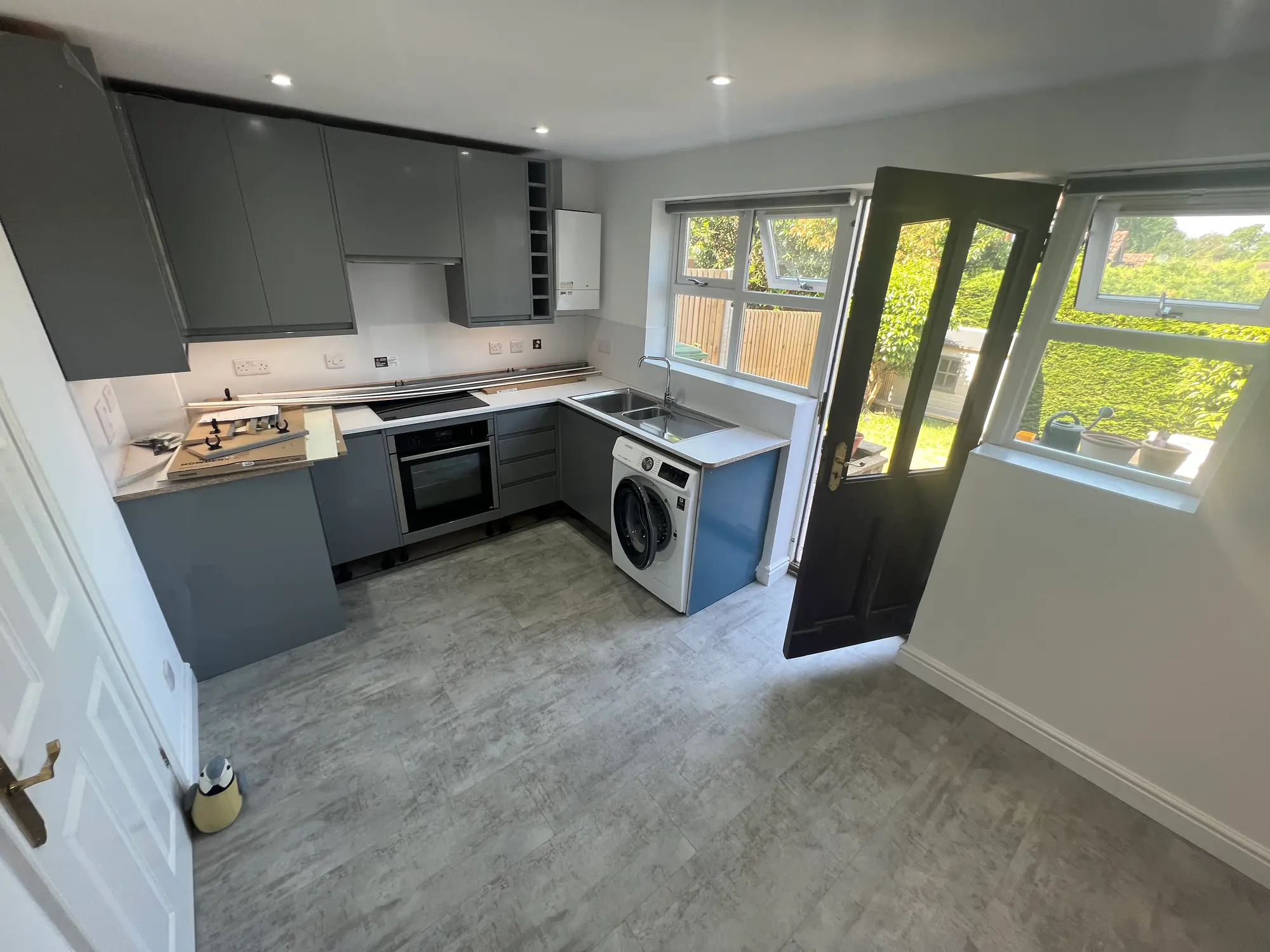 Finished grey fitted kitchen with pale flooring and a glazed garden door