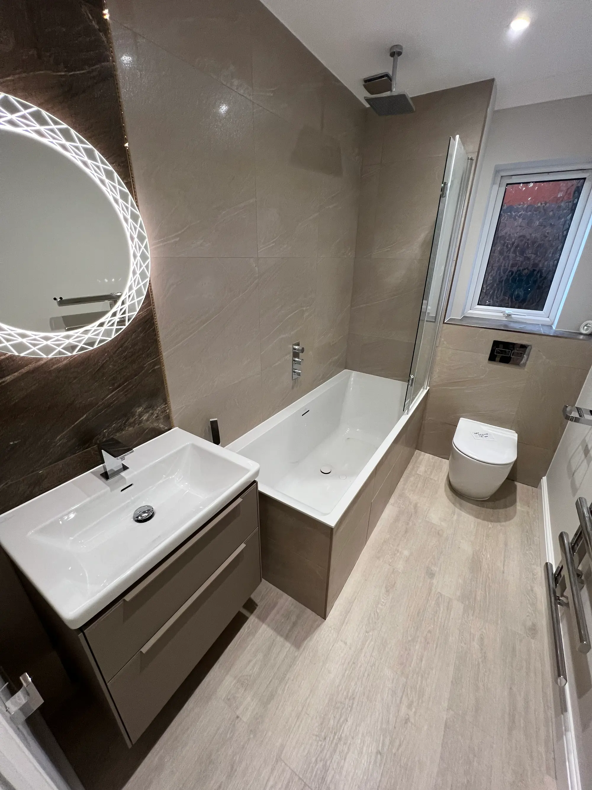 Finished light stone bathroom with a bath and wall-hung toilet