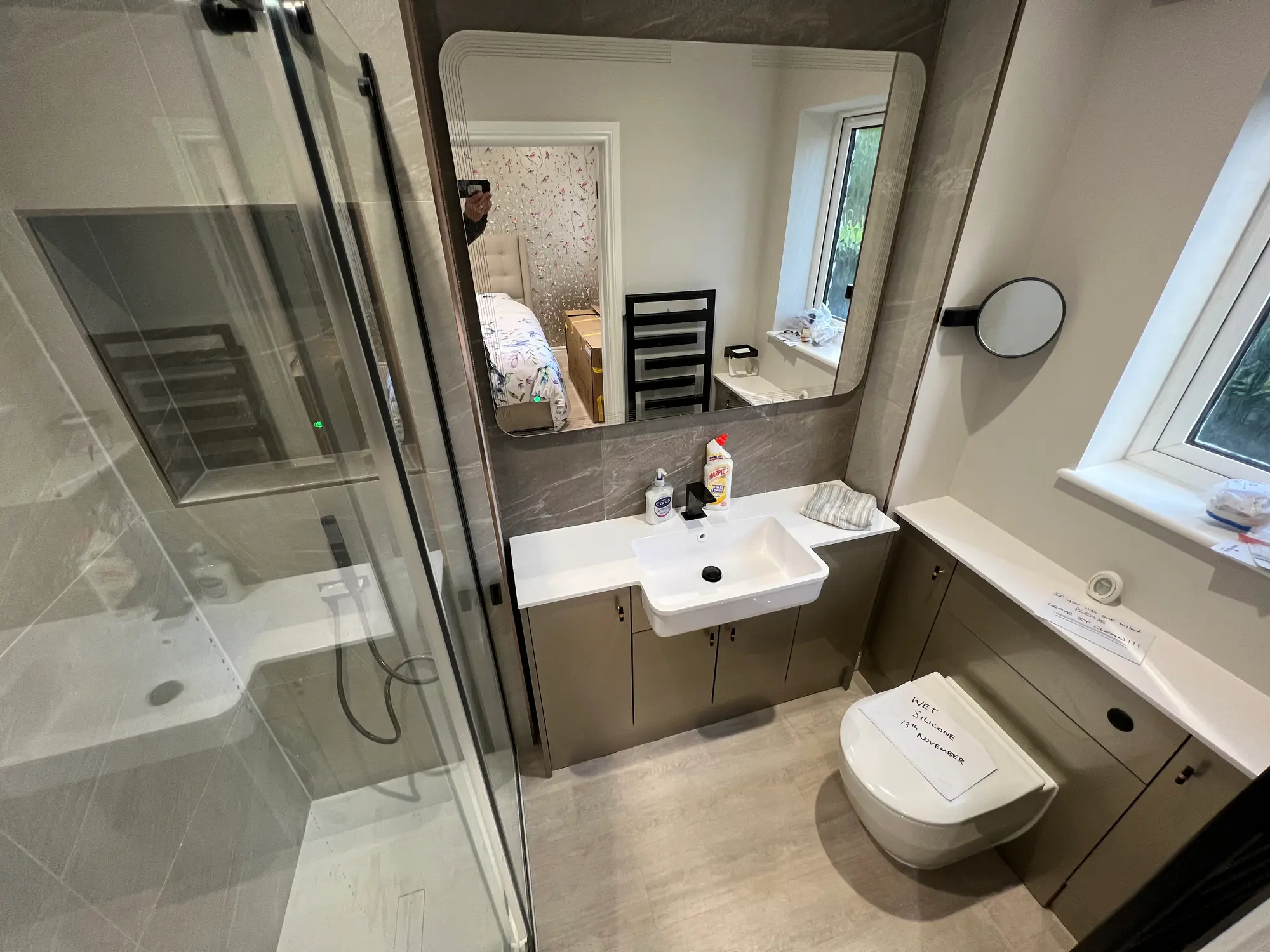 Compact shower and vanity area finished in light stone tiles