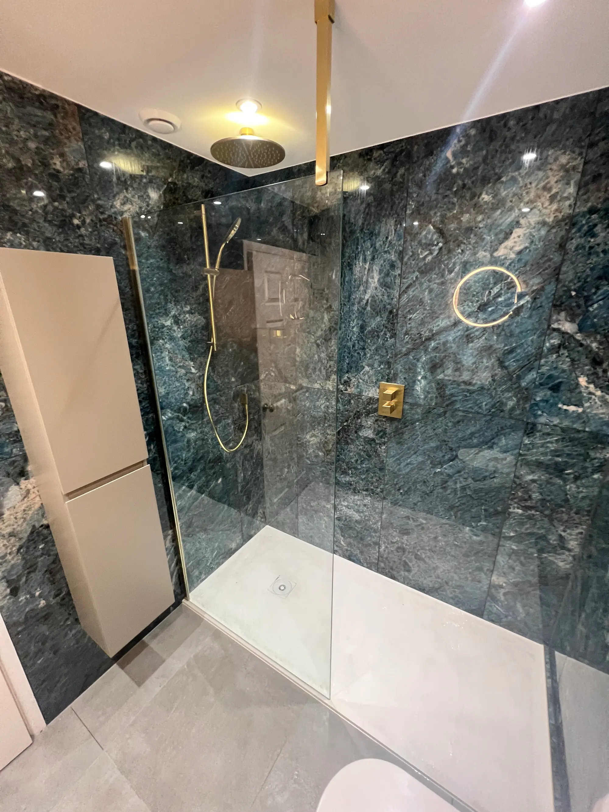 Green marble walk-in shower with brass controls and a clear screen