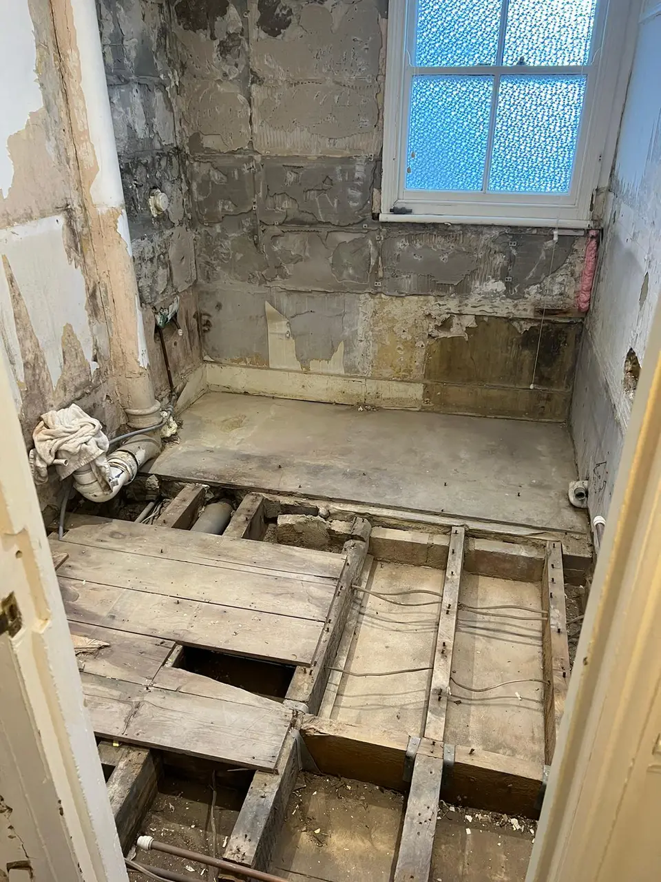 Stripped bathroom with exposed floor joists and old wall finishes removed