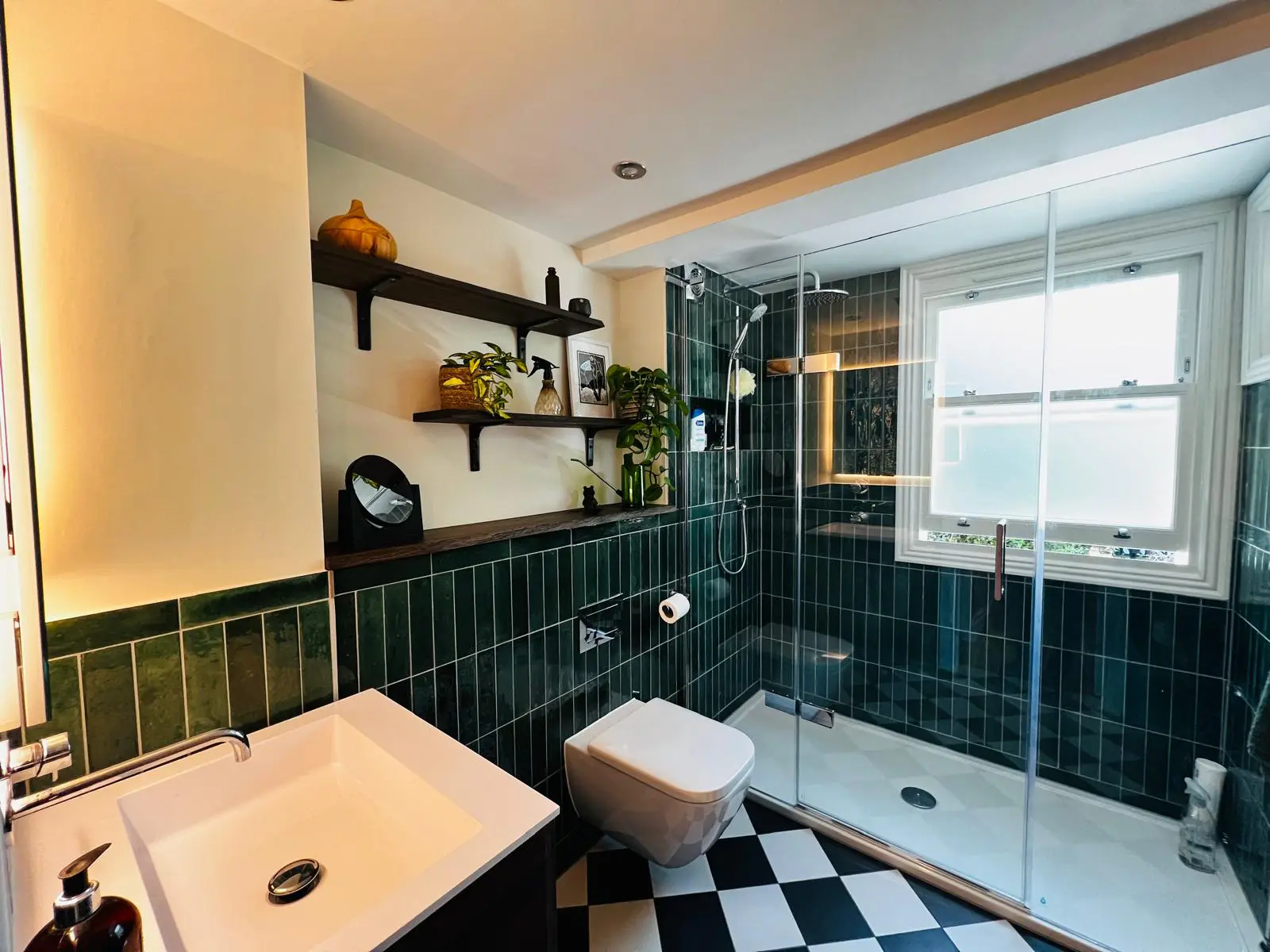 Finished green tiled shower room with wall shelves and a chequered floor