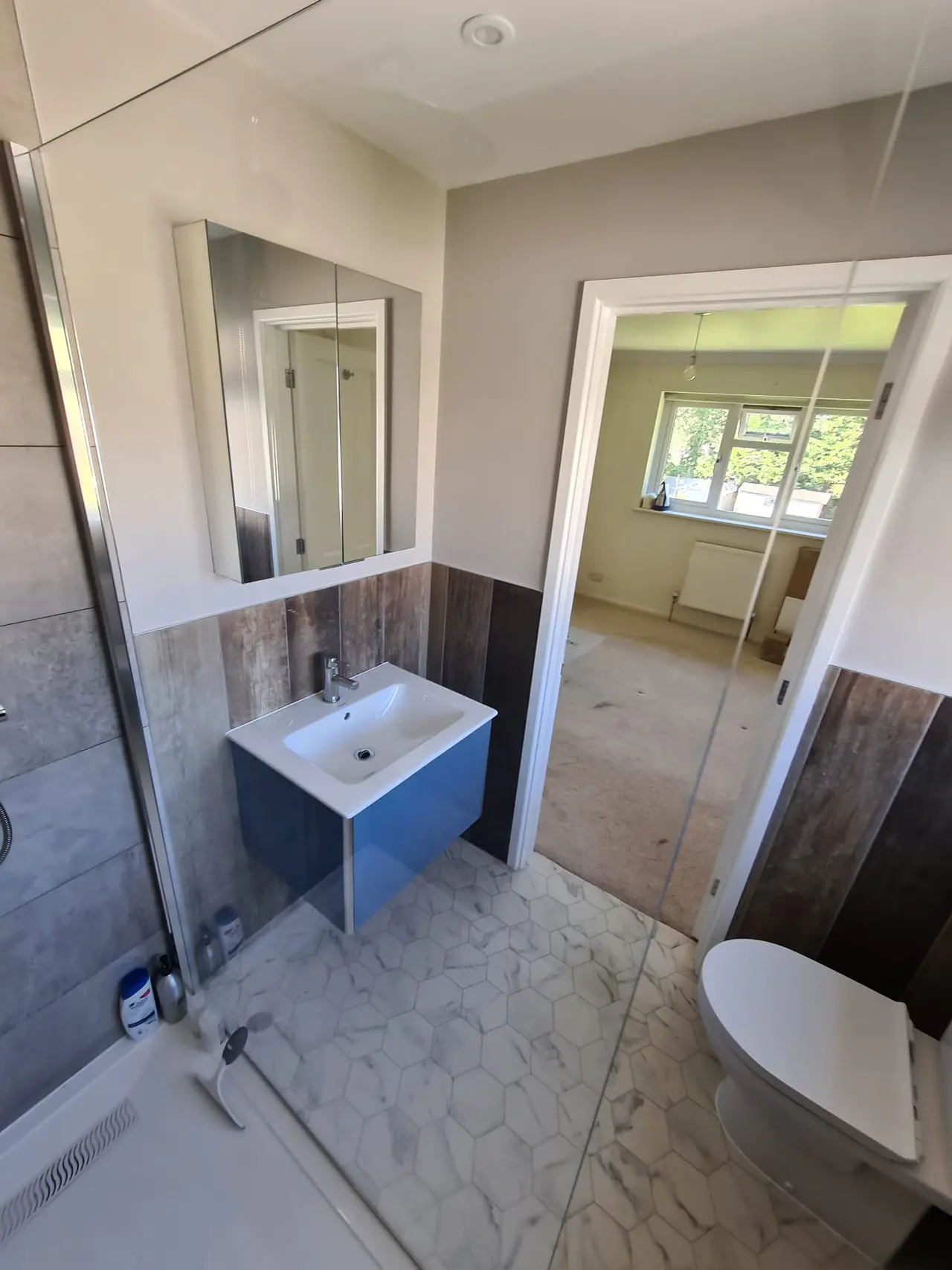 Grey shower room with wood-look wall panels and a blue vanity