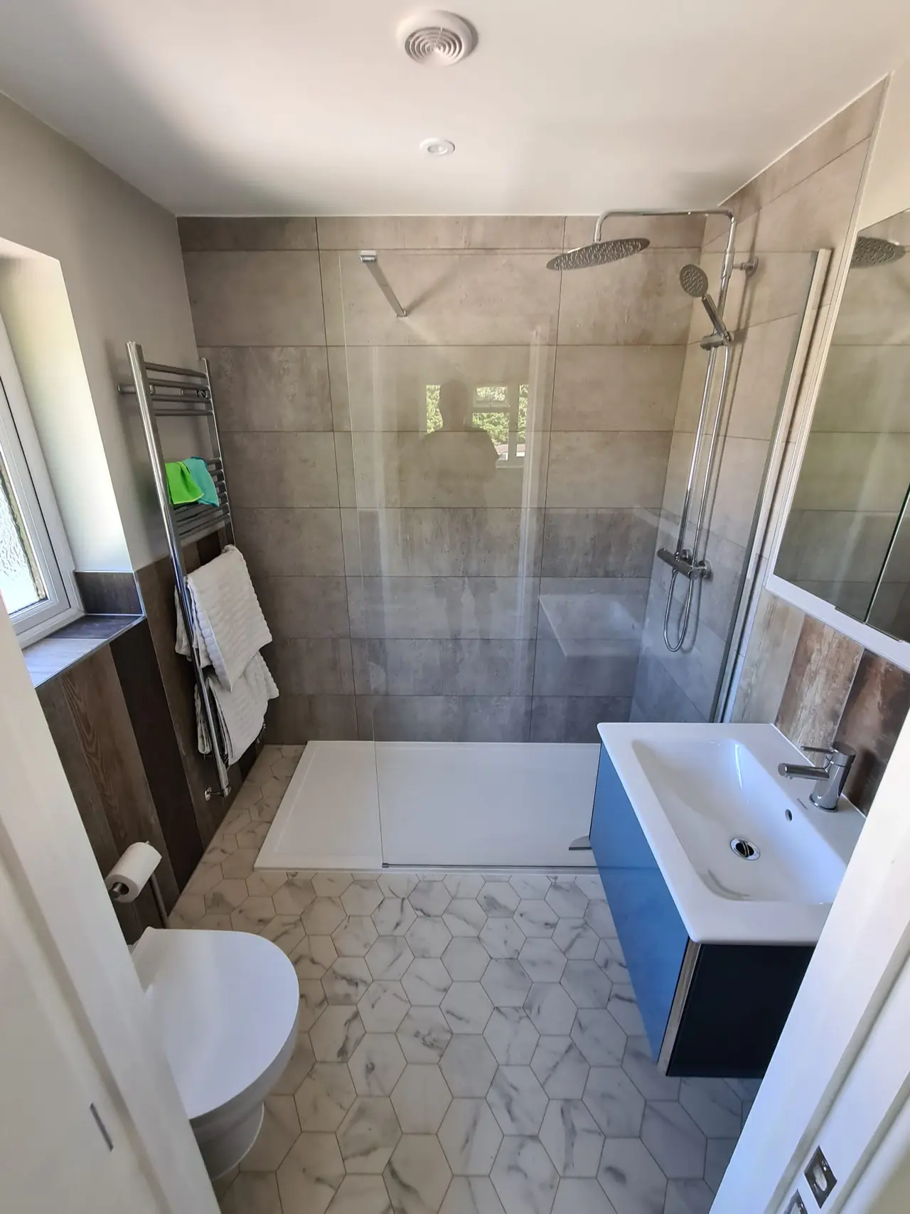 Walk-in shower with concrete-effect tiles and a marble hexagon floor