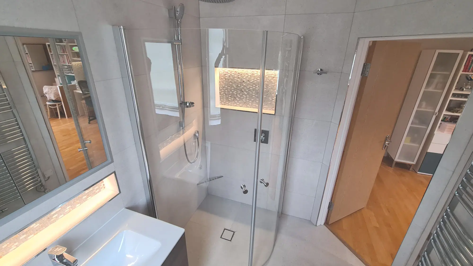 Grey walk-in shower with a rainfall head and illuminated mosaic niche